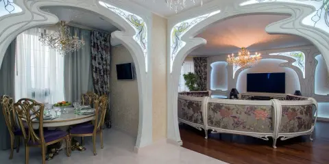 Ett lyxigt vardagsrum och matsal i art nouveau jugendstil med blommig soffa, kristallkronor och utsmyckade valv.