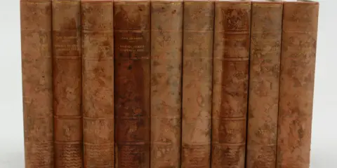 En samling böcker av Carl Grimberg, "Svenska folkets underbara öden", i åtta volymer med slitna läderomslag och guldfärgad text.