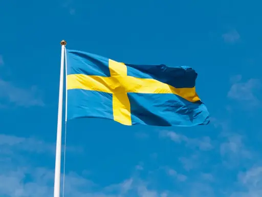 Svenska flaggan vajar i blå himmel. Dess korsdesign har en lång svenska flaggan historia, symboliserande nationens arv.