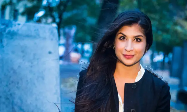 Soraya Hashim ler mot kameran, hennes mörka hår blåser i vinden.