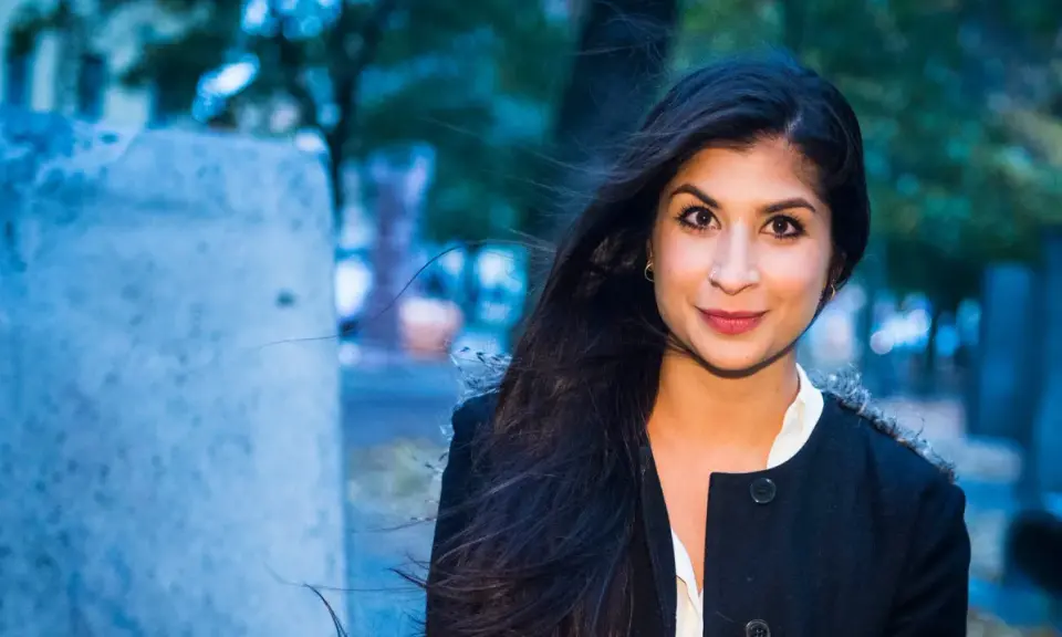 Soraya Hashim ler mot kameran, hennes mörka hår blåser i vinden.
