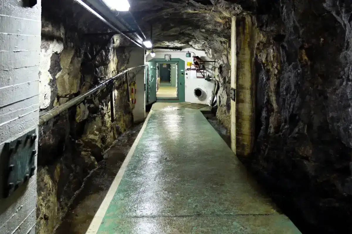 En l&aring;ng, fuktig tunnel i berg med st&aring;ld&ouml;rrar, en p&aring;minnelse om det kalla kriget och Sveriges beredskap.