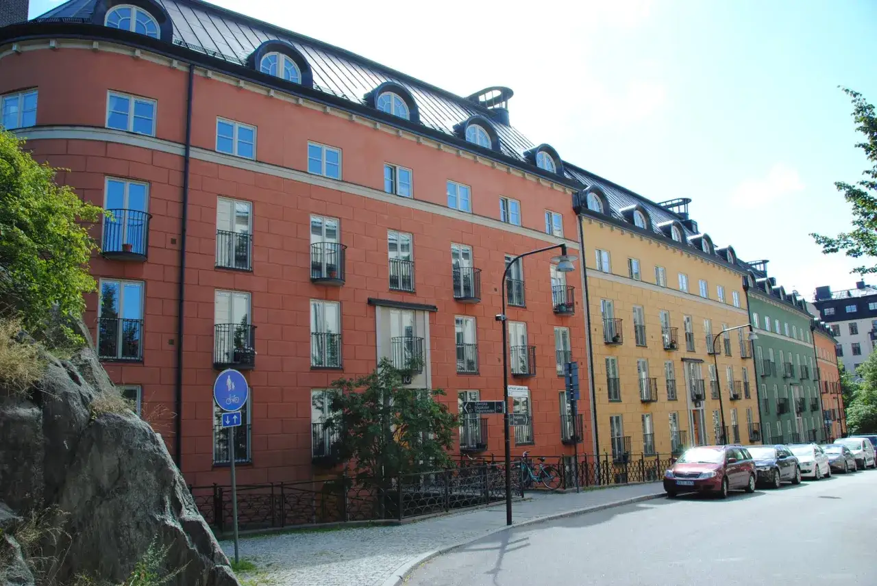 Färgglada hus längs en gata i Stockholm, Nordens Aten, med cyklar och bilar parkerade.